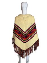 Load image into Gallery viewer, Mannequin wearing a beige knitted garment with colorful pattern and fringes on a plain background

