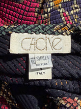 Load image into Gallery viewer, Close-up of a patterned fabric with a 'Cache" label on a multicolored background.
