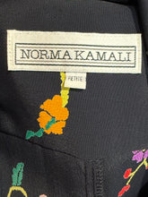 Load image into Gallery viewer, Close-up of a black garment with embroidered flowers and a Norma Kamali label.
