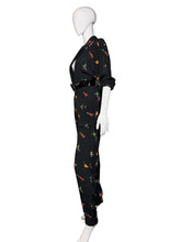 Load image into Gallery viewer, Black jumpsuit with colorful floral pattern on mannequins against a white wall.
