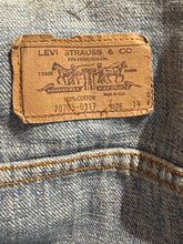 Load image into Gallery viewer, A close-up of a vintage Levi's 707 '100% Cotton' denim patch on a blue denim fabric, showing gold contrast stitching.
