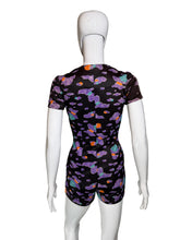 Load image into Gallery viewer, A short-sleeve romper displayed on a white mannequin from the back, featuring a black base with a colorful abstract cloud-like pattern in purple, teal, and orange.
