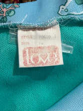 Load image into Gallery viewer, Close-up of a fabric garment tag that reads 'LOVE' logo and printed size/style information.
