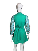 Load image into Gallery viewer, A green dress displayed on a white mannequin, featuring a solid green gathered skirt and light blue floral long sleeves.
