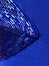 Load image into Gallery viewer, Close-up of a blue beaded fabric corner with iridescent rectangular beads on a solid royal blue textile background.
