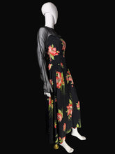 Load image into Gallery viewer, A black midi dress with a vibrant red and pink floral print and sheer black long sleeves, displayed on a white mannequin in front of a black background.
