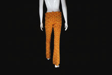 Load image into Gallery viewer, A pair of flared trousers with a textured orange and yellow geometric pattern, displayed on a white mannequin.
