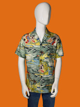 Load image into Gallery viewer, A mannequin wearing a short-sleeve button-up shirt with a colorful tropical floral and wave print, paired with blue jeans against a black background.
