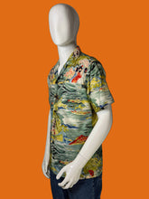 Load image into Gallery viewer, A short-sleeve button-up shirt with a colorful tropical floral and ocean print, displayed on a white mannequin against a black background.
