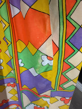 Load image into Gallery viewer, A close-up of a colorful patterned fabric with geometric shapes and floral motifs in yellow, orange, green, purple, and white. Photo displays some discoloration in the fabric.
