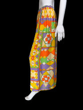 Load image into Gallery viewer, A mannequin wearing a long skirt with a bold geometric and floral pattern in yellow, orange, purple, green, and cream.
