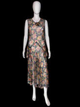 Load image into Gallery viewer, A sleeveless dress with a floral print. The dress features a navy blue base with pink, red, and green floral patterns, and a ruffled asymmetrical hem.
