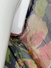 Load image into Gallery viewer, A close-up of a draped fabric with a large-scale floral pattern in muted pink, green, beige, and gray tones, shown next to a white surface. Photo shows a small tear in the armpit. 
