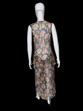 Load image into Gallery viewer, A sleeveless dress with a floral print. The dress features a navy blue base with pink, red, and green floral patterns, and a ruffled asymmetrical hem.
