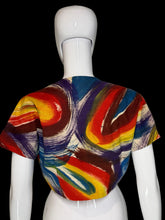 Load image into Gallery viewer, A short-sleeve cropped shrug or bolero jacket with a matching abstract brushstroke pattern in red, yellow, blue, and cream, displayed on a white mannequin torso.
