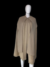 Load image into Gallery viewer, A beige ribbed knit cape with a draped collar and layered hem, displayed on a white mannequin.
