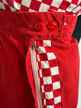 Load image into Gallery viewer, Close-up of a red garment showing a red-and-white checkered fabric panel, three red buttons, and a metalzipper.
