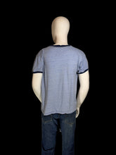 Load image into Gallery viewer, A heather blue ringer t-shirt with dark navy trim on a white mannequin shown from the back.
