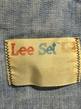 Load image into Gallery viewer, A close-up of a denim garment's interior label reading 'Lee Set' in red and blue text on a beige fabric tag, bordered by black zigzag stitching, set against a blue denim background.

