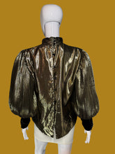 Load image into Gallery viewer, A back view of a metallic gold pleated blouse with black long sleeves and a high mock neck, shown on a white mannequin.
