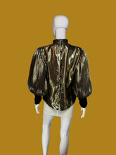 Load image into Gallery viewer, A metallic gold pleated blouse with black long sleeves and a high mock neck, shown on a white mannequin.
