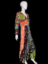 Load image into Gallery viewer, A long-sleeved patchwork maxi dress displayed on a mannequin. The dress features a vibrant multicolor patchwork design with various patterns including houndstooth, polka dots, florals, and plaid in orange, green, pink, black, white, and purple
