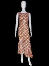 Load image into Gallery viewer, A 1930's sleeveless V-neck midi dress with a diagonal plaid pattern in red and black on a beige base on a white mannequin.
