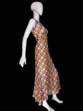 Load image into Gallery viewer, A 1930's sleeveless V-neck midi dress with a diagonal plaid pattern in red and black on a beige base on a white mannequin.
