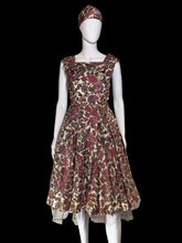 Load image into Gallery viewer, A sleeveless fit-and-flare dress with a matching headband displayed on a white mannequin. The dress features a floral pattern in dusty pink, burgundy, and olive green.
