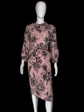 Load image into Gallery viewer, A pink midi dress with a black floral and botanical print, displayed on a white mannequin.
