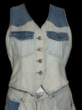 Load image into Gallery viewer, A sleeveless denim vest top with a light blue and white vertical stripe pattern, featuring a darker blue denim yoke at the shoulders, two chest pockets with metal snap buttons, and a row of decorative gold-tone buttons down the front, displayed on a white mannequin torso.
