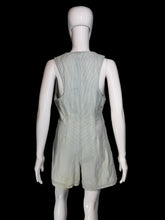 Load image into Gallery viewer, A light gray denim romper displayed on a white mannequin from the back, set against a plain light gray wall.
