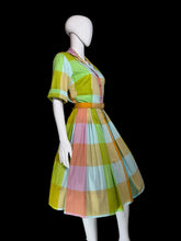 Load image into Gallery viewer, A multicolor plaid midi dress displayed on a white mannequin. The dress features a vibrant checkered pattern of lime green, yellow, pink, orange, and light blue, with a matching waist belt.
