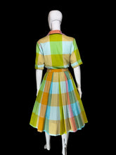 Load image into Gallery viewer, A vintage plaid dress displayed on a white mannequin, viewed from the back. The dress features a colorful checkered pattern with yellow, green, orange, blue, and pink blocks.
