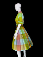 Load image into Gallery viewer, A retro A-line dress with a colorful pastel block check pattern, displayed on a white mannequin in a side profile view.
