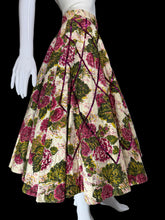 Load image into Gallery viewer, A vintage-style full skirt with a floral print on a cream background, featuring large pink and green flowers with dark purple ribbon accents, displayed on a white mannequin.

