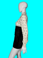 Load image into Gallery viewer, A one piece romper displayed on a white mannequin, featuring a long-sleeve button-down top with a black cat print on a white background, and high-waisted black velvet shorts.
