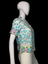 Load image into Gallery viewer, A short-sleeve collared blouse with a blue, pink, and green floral print on a cream background, displayed on a white mannequin.

