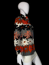 Load image into Gallery viewer, A long-sleeve knit top with a bold retro floral and striped pattern in orange, black, white, and gray, displayed on a white mannequin.
