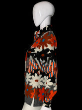 Load image into Gallery viewer, A long-sleeve collared blouse with a bold retro floral and striped pattern in orange, black, white, and gray, displayed on a white mannequin.
