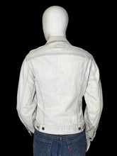 Load image into Gallery viewer, A white denim jacket displayed on a white mannequin from the back, paired with blue jeans.
