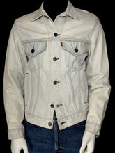Load image into Gallery viewer, A light-wash denim trucker jacket displayed on a white mannequin torso, paired with blue jeans.
