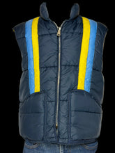 Load image into Gallery viewer, A navy blue puffer vest with bright yellow and light blue vertical stripes on the front, displayed on a white mannequin torso with blue jeans visible at the bottom.
