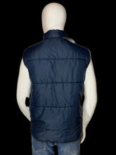 Load image into Gallery viewer, A navy blue quilted puffer vest displayed on a white mannequin from the back, paired with blue jeans.
