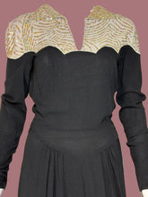 Load image into Gallery viewer, A black long-sleeve dress displayed on a mannequin, featuring a scalloped yoke with shimmering gold and beige sequined embroidery with a v neck. 
