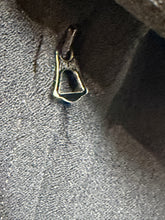 Load image into Gallery viewer, A close-up of a small metallic zipper pull attached to a gray textured fabric surface.
