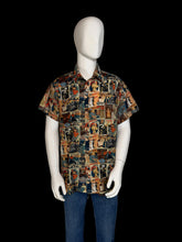 Load image into Gallery viewer, A short-sleeve button-up shirt displayed on a white mannequin. The shirt features a dense collage print of magazine cover illustrations in a multicolor palette of blue, red, beige, and brown.
