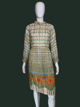 Load image into Gallery viewer, A long-sleeve midi dress with a pleated texture, featuring a beige base with colorful horizontal stripes and a vibrant geometric pattern near the hem, displayed on a white mannequin.
