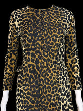 Load image into Gallery viewer, A close up of a long-sleeve leopard-print dress displayed on a white mannequin. The dress features a bold black and tan/gold animal print pattern with a button-up front and side pockets.
