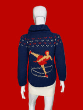 Load image into Gallery viewer, A navy blue knit zip-up cardigan sweater with a hood, featuring two large red and beige dancer motifs on the front, displayed on a white mannequin.
